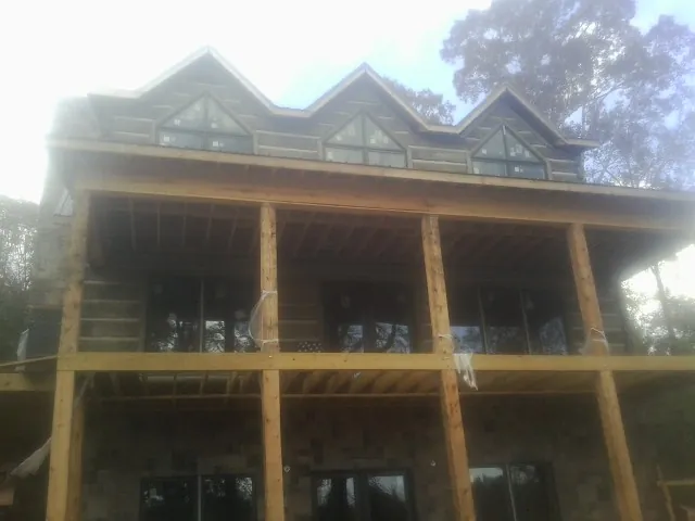 Dormers and porch framing on a large log home under construction — Roof Coating work by our crew in Blandon