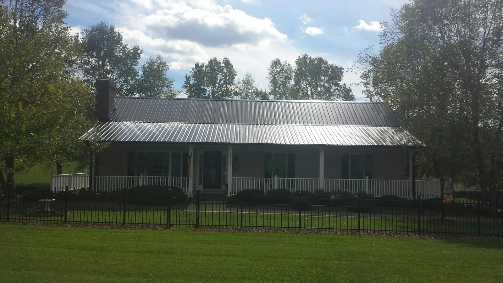Gray metal roof on a brick ranch with a full width front porch — Gutter Guard Installation work by our crew in Blandon