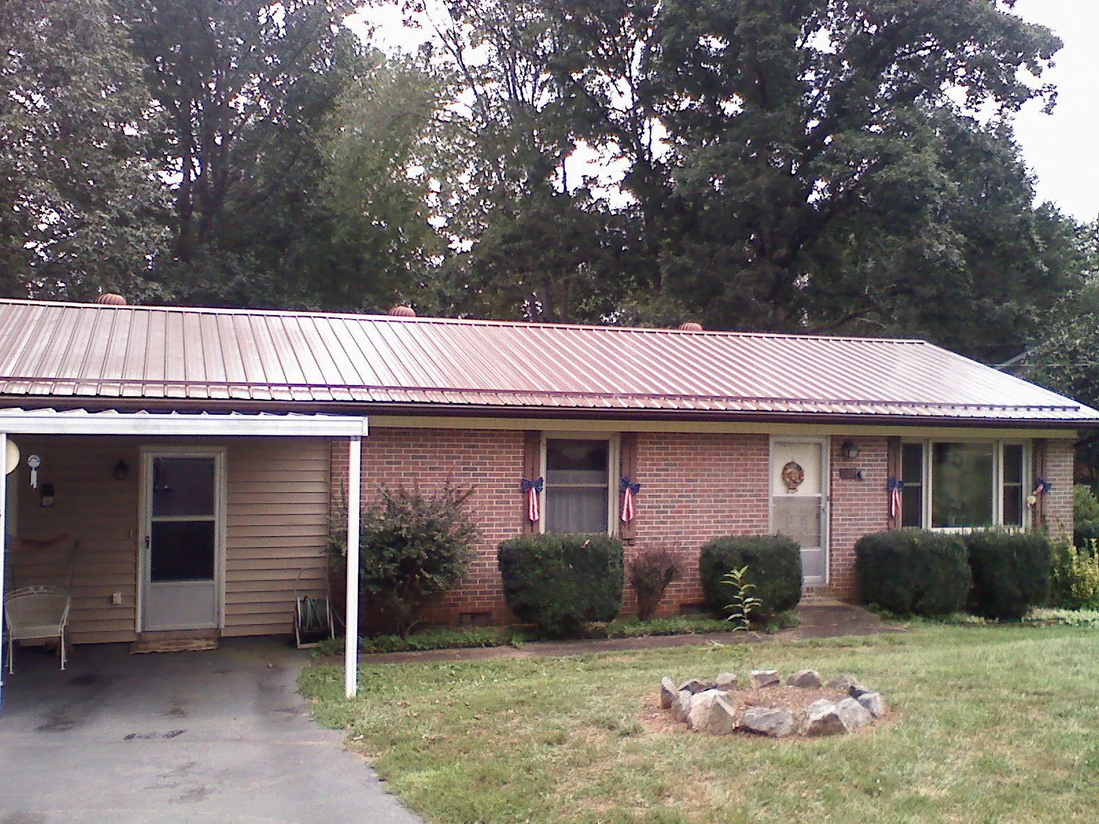 Bronze metal roof and carport on a brick ranch home — Roof Repair work by our crew in Blandon