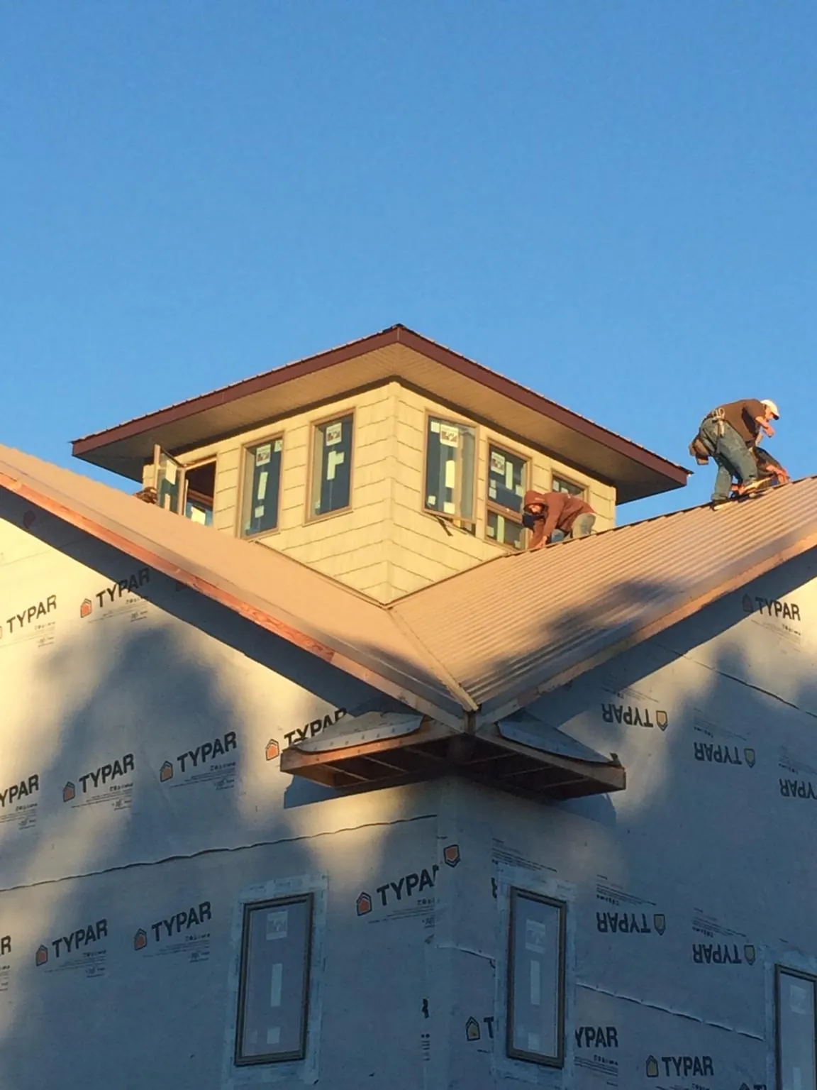 Roofers working around a rooftop cupola on a new metal roof at sunset — Roof Waterproofing in Blandon by Roofing Brothers